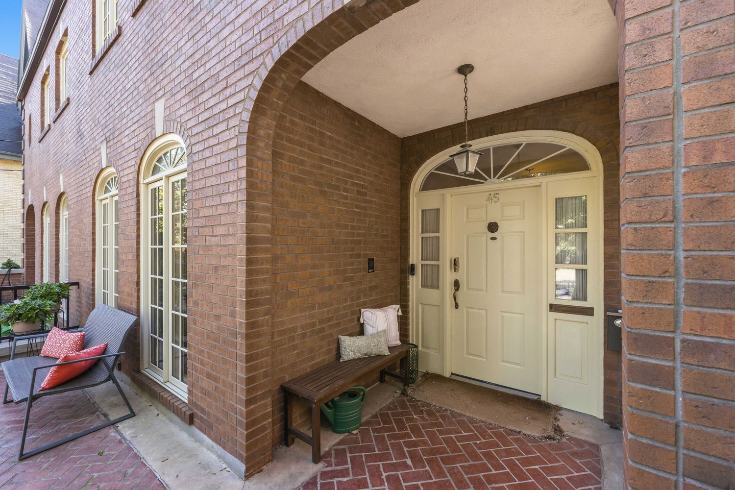 Covered front porch with arched brick entryway and house number 45
